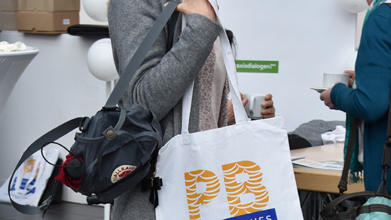 Junge Frau mit einer Stofftasche, auf der das Logo der Persönlichen Budget-Kampagne aufgedruckt ist.