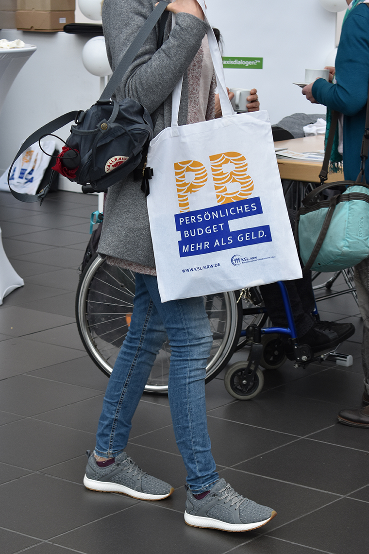 Junge Frau mit einer Stofftasche, auf der das Logo der Persönlichen Budget-Kampagne aufgedruckt ist.