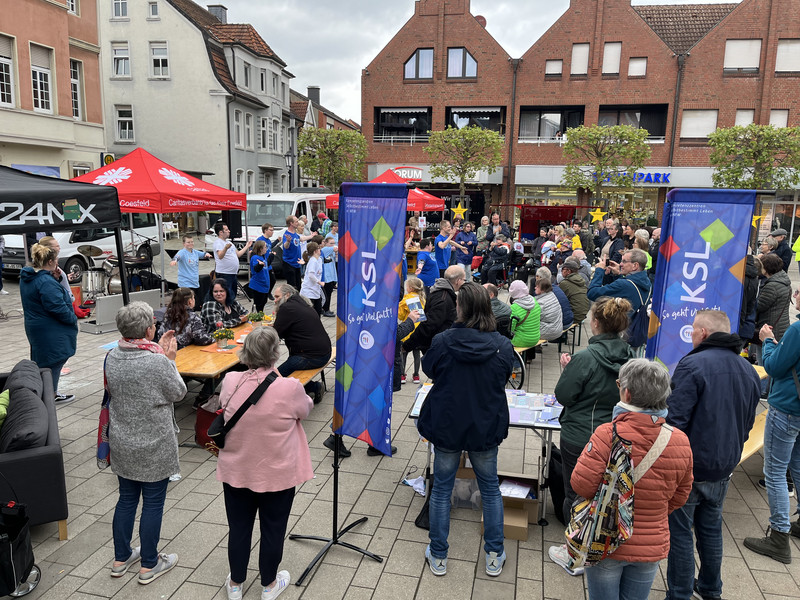 Foto vom Marktplatz in Lüdinghausen. Eine Tanzgruppe tritt auf. Menschen und Infostände drumherum.