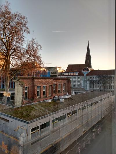 Das Bild zeigt den Ausblick auf dem Fenster des KSL Münster auf die Lambertikriche und das Stadttheater