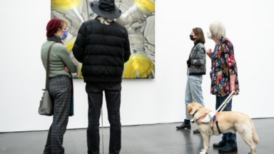 Mehrere Personen - u.a. mit einem Blindenhund - betrachten ein Bild. Foto: Kunsthalle Düsseldorf