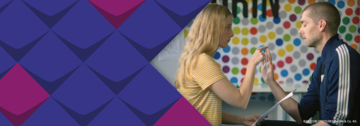 Das Bild zeigt eine Frau und einen Mann. Sie sitzen sich gegenüber und berühren sich.