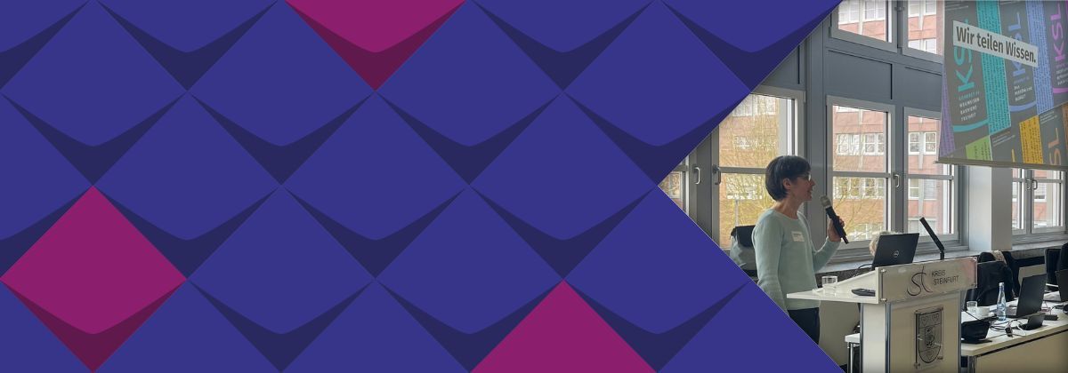 Martina Steinke vom KSL.Münster steht bei einer Veranstaltung am Rednerpult mit einem Mikrofon in der Hand. Im Hintergrund ist eine Präsentation der KSL.NRW auf einer Leinwand zu sehen. Auf der Folie steht "Wir teilen Wissen."