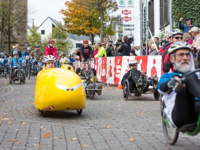 Der GIRO inklusiv rollt! Ein knallgelbes Liegerad rollt an den Zuschauern vorbei.
